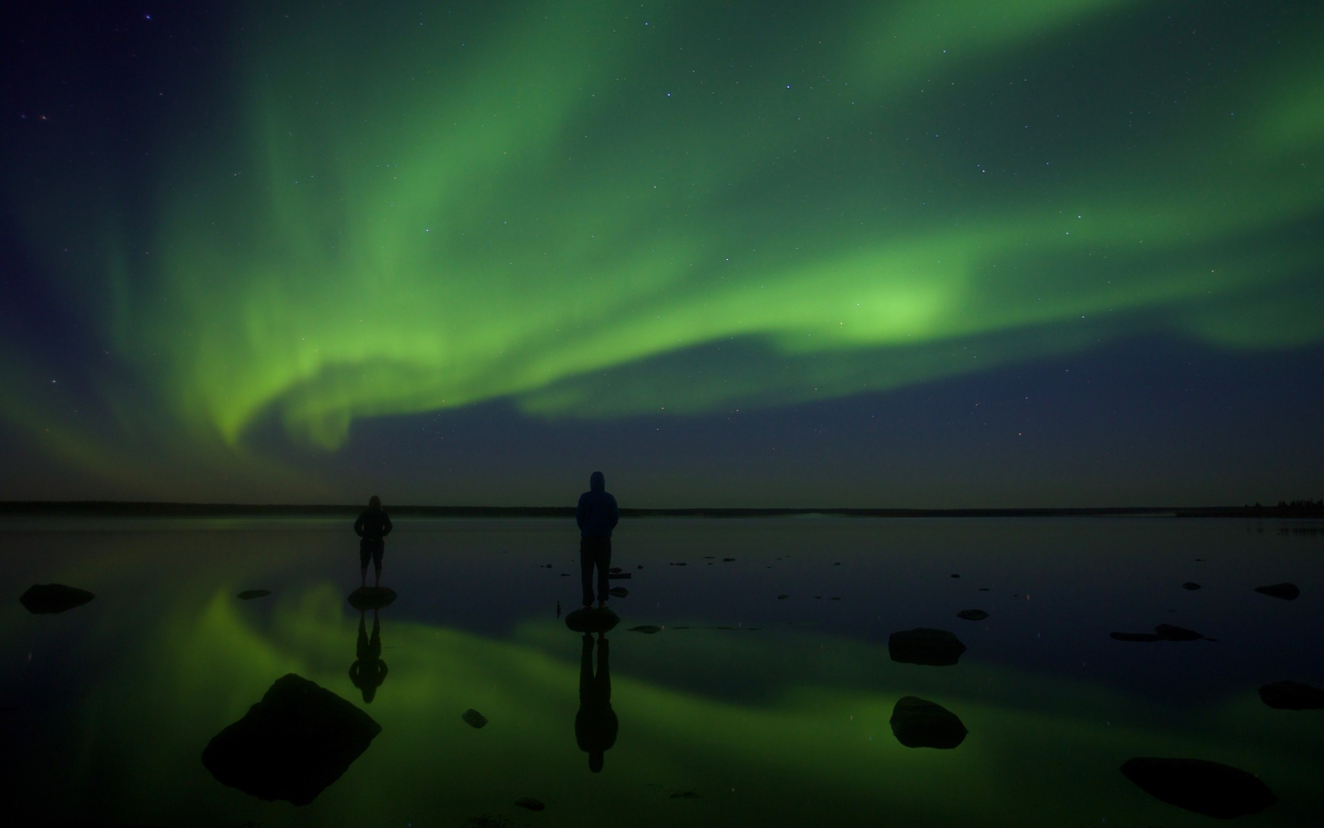 Guests enjoying the northern lights, lakeside at Arctic Haven.